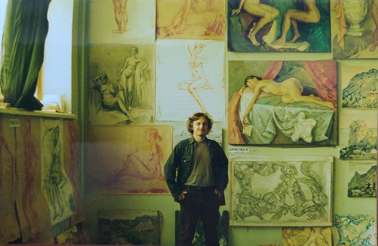 Leonid Pavlenko standing in front of his drawings and paintings